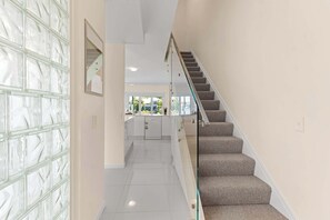 A modern interior with a staircase, a kitchen area, and a glass door.