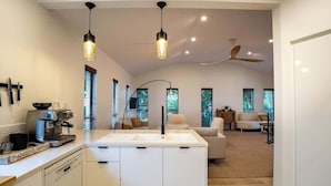 Una cocina moderna con una isla central, luces colgantes y un ventilador de techo.