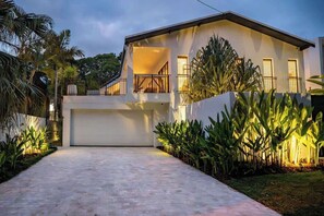 A modern two-story house with a garage, surrounded by tropical plants. - Spacious & Stylish Family Oasis on Noosa Hill (Noosa Region)