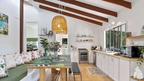 A modern kitchen with white cabinets, a wooden bench, and a dining table.