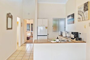 A kitchen with a wooden countertop, a refrigerator, and a coffee machine. - Prime Noosa Location with Pool (Noosa Region)