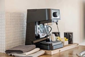 A coffee machine on a countertop with a tray, a cloth, and a mug. - Prime Noosa Location with Pool (Noosa Region)