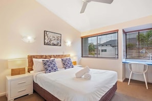 A bedroom with a bed, bedside tables, a desk, and a chair. - Prime Noosa Location with Pool (Noosa Region)