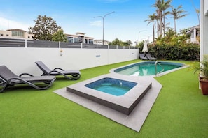 A pool area with artificial grass, two pools, and lounge chairs. - Prime Noosa Location with Pool (Noosa Region)