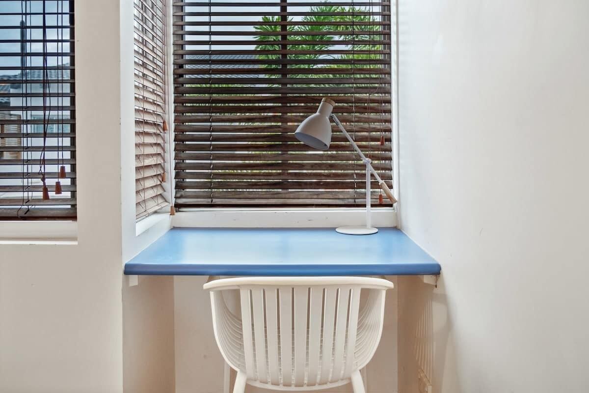 A corner desk with a blue surface, a white chair, and a desk lamp.