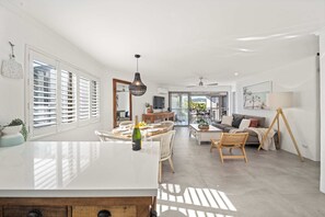 A spacious living area with a dining table, chairs, a sofa, and a swing. - Sandy Daze - Noosa Sound Canalfront Apartment (Noosa Region)