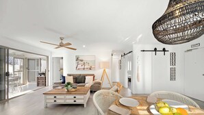 Un soggiorno moderno con tavolo da pranzo, divano e ventola a soffitto.