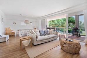 Ein modernes Wohnzimmer mit einer Couch, einem Esstisch, Stühlen und einem Korbsessel.