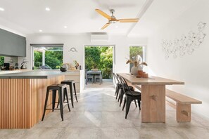 Une cuisine moderne dotée d’un îlot central, de tabourets de bar, d’un banc en bois et d’un ventilateur de plafond.