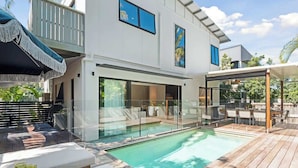 Een modern huis met een zwembad, buitenmeubilair en een balkon.