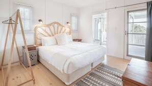 A bedroom with a bed, bedside tables, a wooden ladder, and a view of the outdoors. - Little Red Barn in the Noosa Hinterland (Hinterland Region)
