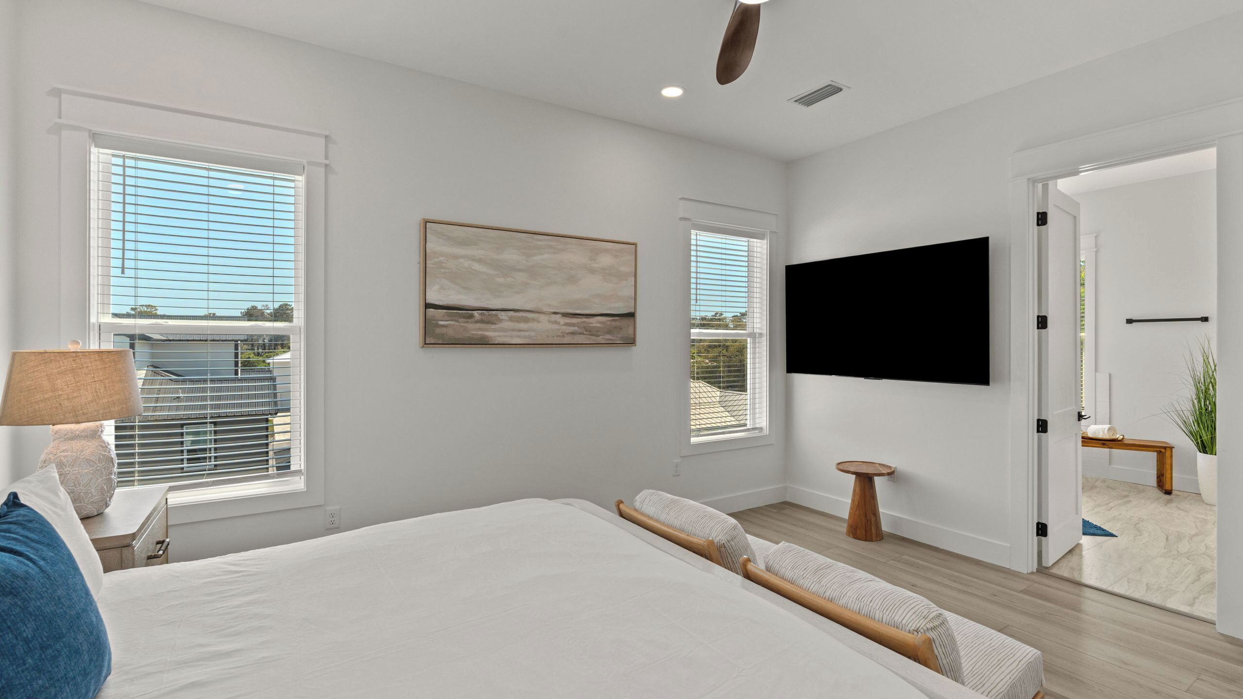 A modern bedroom with a large bed, a TV, and a painting on the wall.