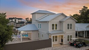 Ein zweistöckiges Haus mit überdachter Terrasse und Swimmingpool.