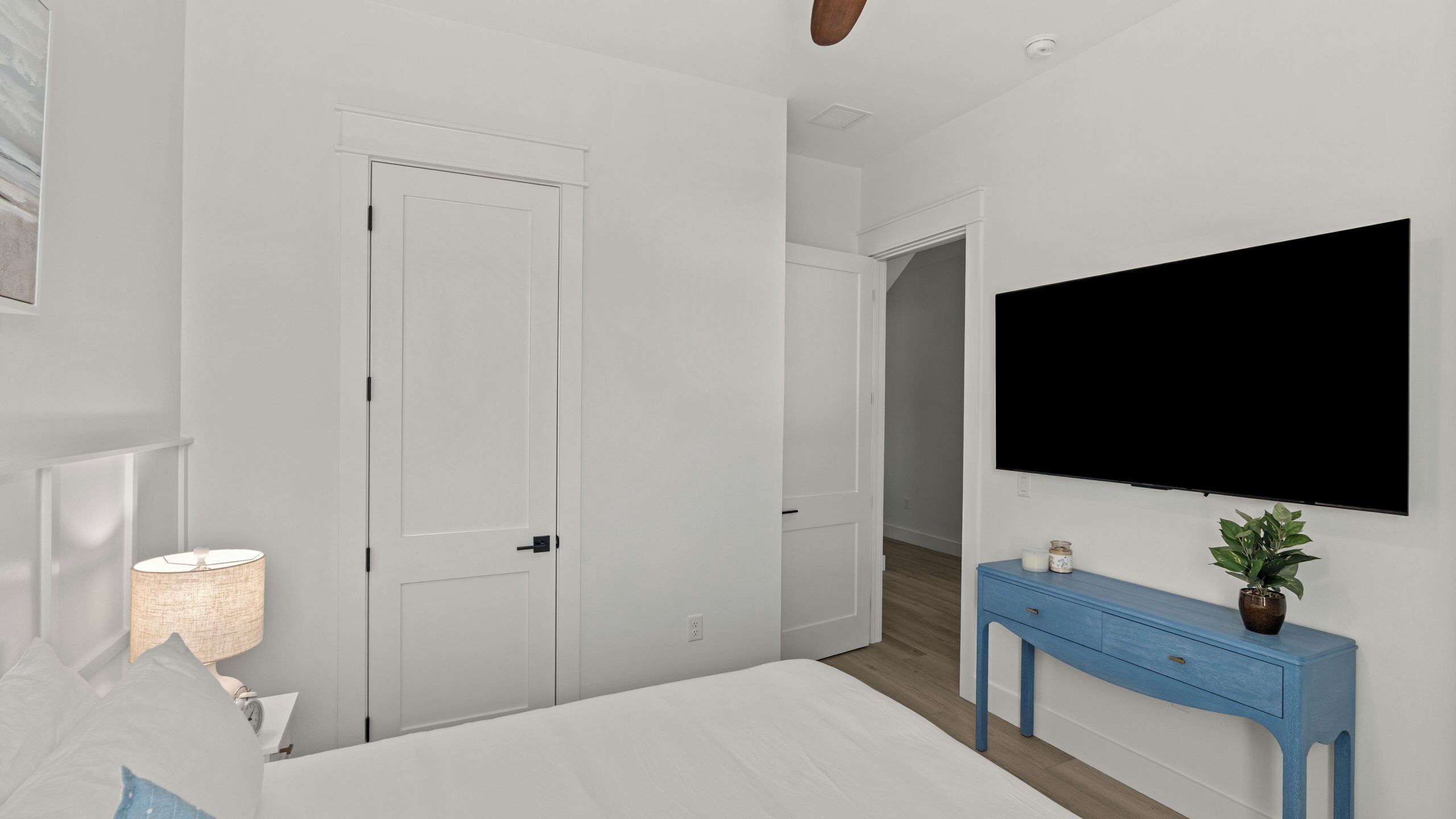 A bedroom with a bed, a TV, a blue dresser, and a door.