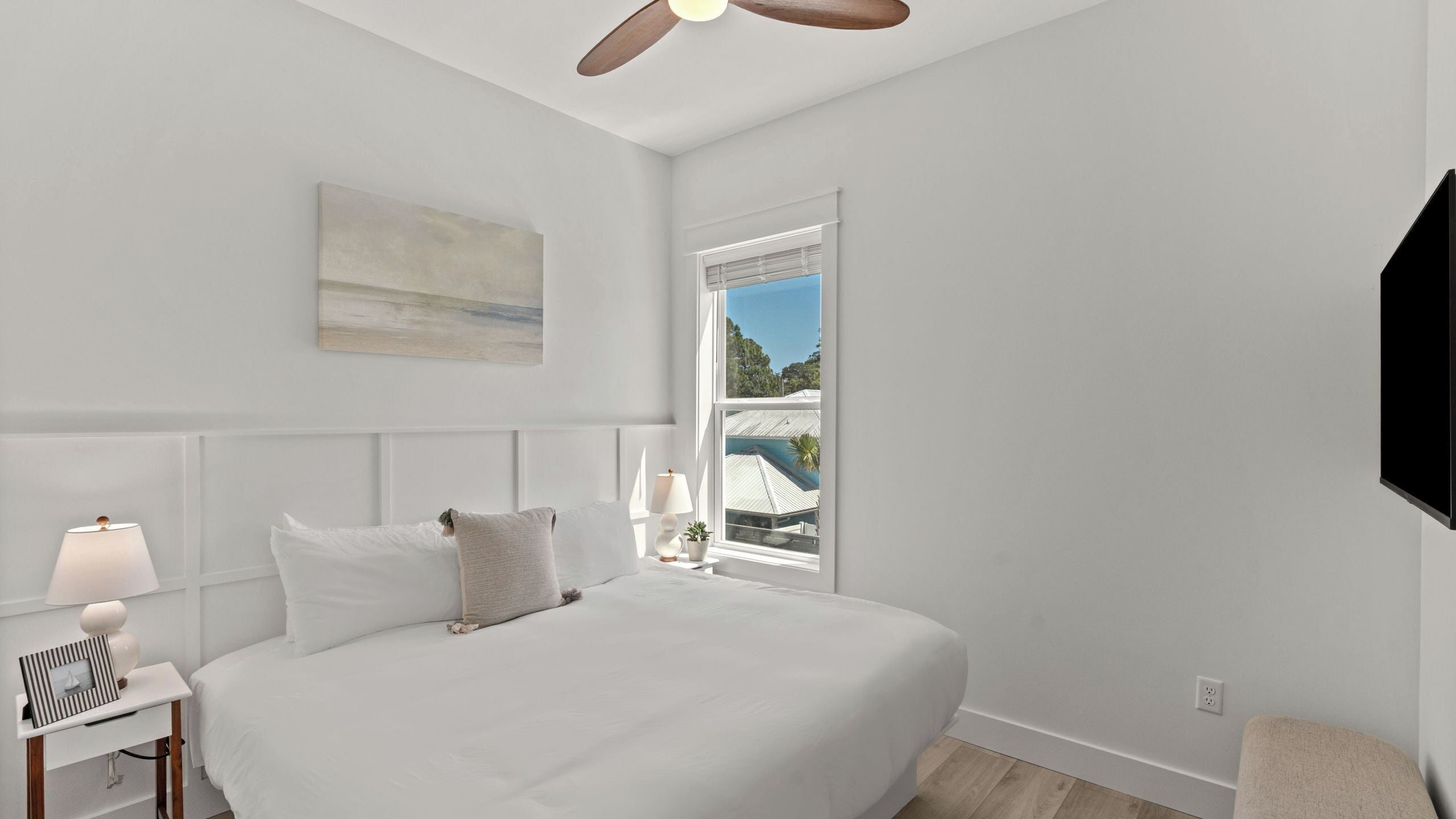 A bedroom with a bed, bedside table, lamp, and a painting on the wall.