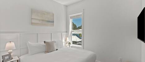 A bedroom with a bed, bedside table, lamp, and a painting on the wall.