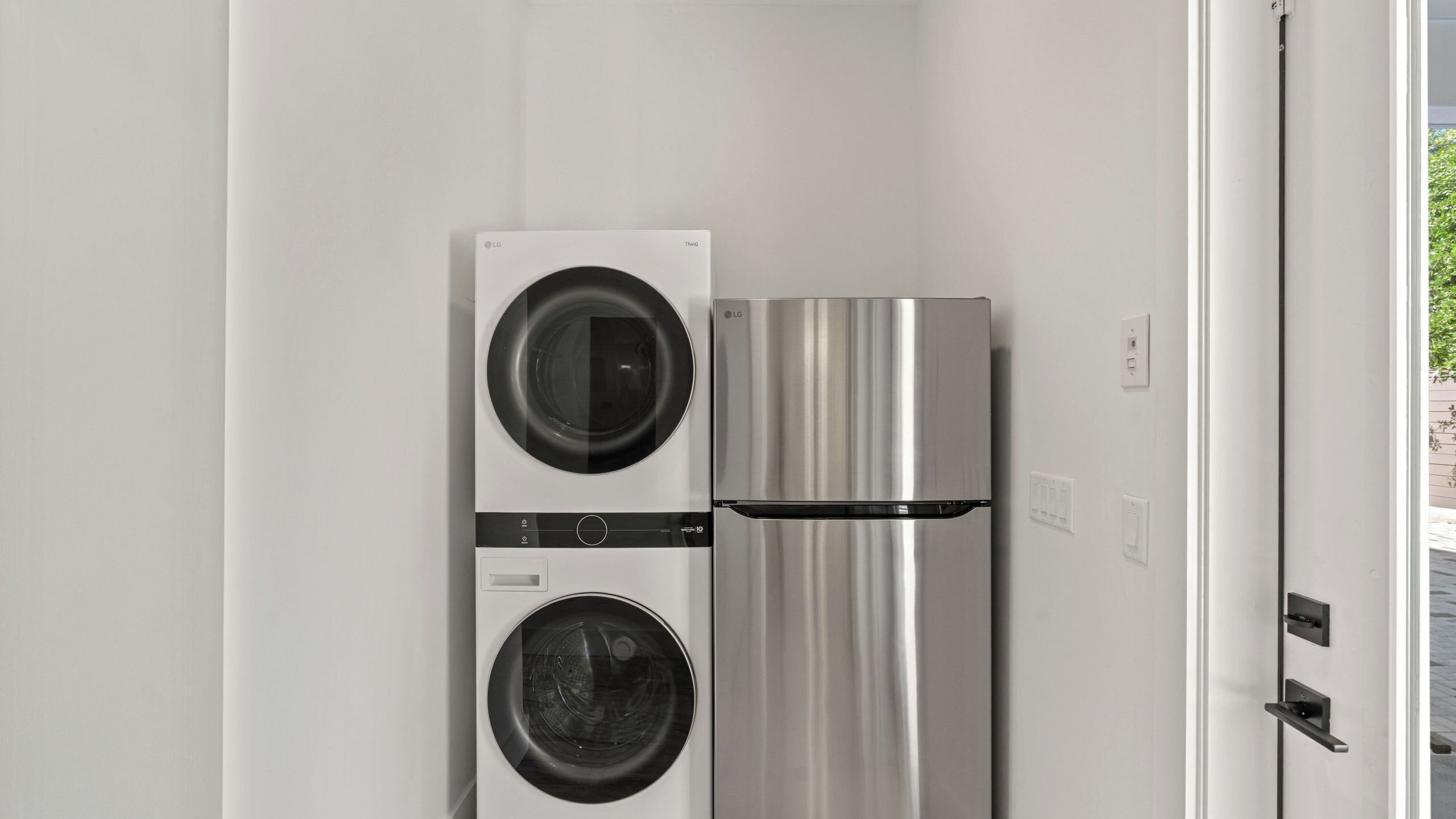 A compact kitchen with a stainless steel refrigerator and a washing machine.