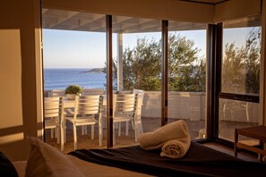 Una habitación con cama, ventana con vista al mar y zona de estar con sillas y mesa.