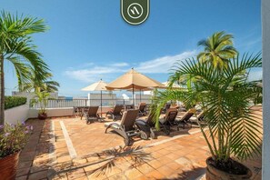 Eine Dachterrasse mit Liegestühlen, Sonnenschirmen und Blumentöpfen.