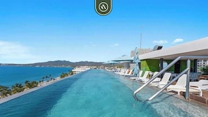 Una piscina larga y despejada, con vistas al océano y montañas en la distancia.