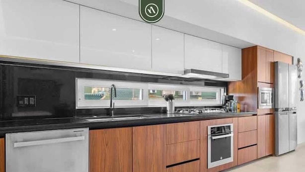 Una cocina moderna con encimera negra, electrodomésticos de acero inoxidable y armarios de madera.
