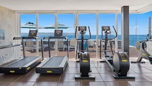 Un gimnasio con cintas de correr, elípticas y una máquina de remo, con vistas panorámicas.