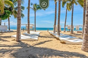 Una playa con tumbonas y palmeras.