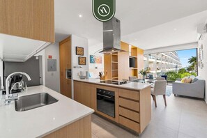 Cocina moderna con una isla central, horno empotrado y vistas a un edificio de hotel.