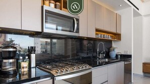 Una cocina moderna con estufa a gas, microondas y alacenas de acero inoxidable.