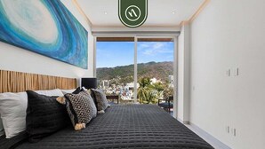 Un dormitorio con una cama grande, vistas a la ciudad y un cuadro en la pared.