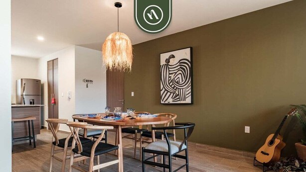 A dining area with a wooden table and chairs, a hanging light fixture, a guitar, and a wall-mounted artwork. - Beautiful House in San Miguel de Allende - Private (San Miguel de Allende)