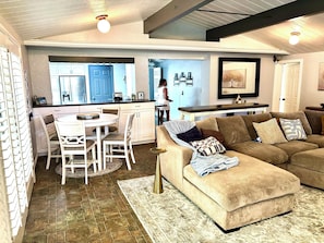 A modern living room with a sectional sofa, a dining area with a white table and chairs, and a kitchen with blue cabinets and a refrigerator. - Spacious 5-bedroom house with breathtaking views  (Murray)