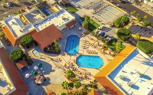 An aerial view of a resort with multiple swimming pools, sun loungers, and palm trees. - Cozy 2-Bedroom House in Yuma, Arizona in a 55+ Resort Community w/Every Amenity (Yuma)