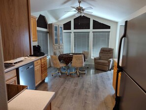A kitchen with a dining table, chairs, a ceiling fan, and a refrigerator. - Cozy 2-Bedroom House in Yuma, Arizona in a 55+ Resort Community w/Every Amenity (Yuma)