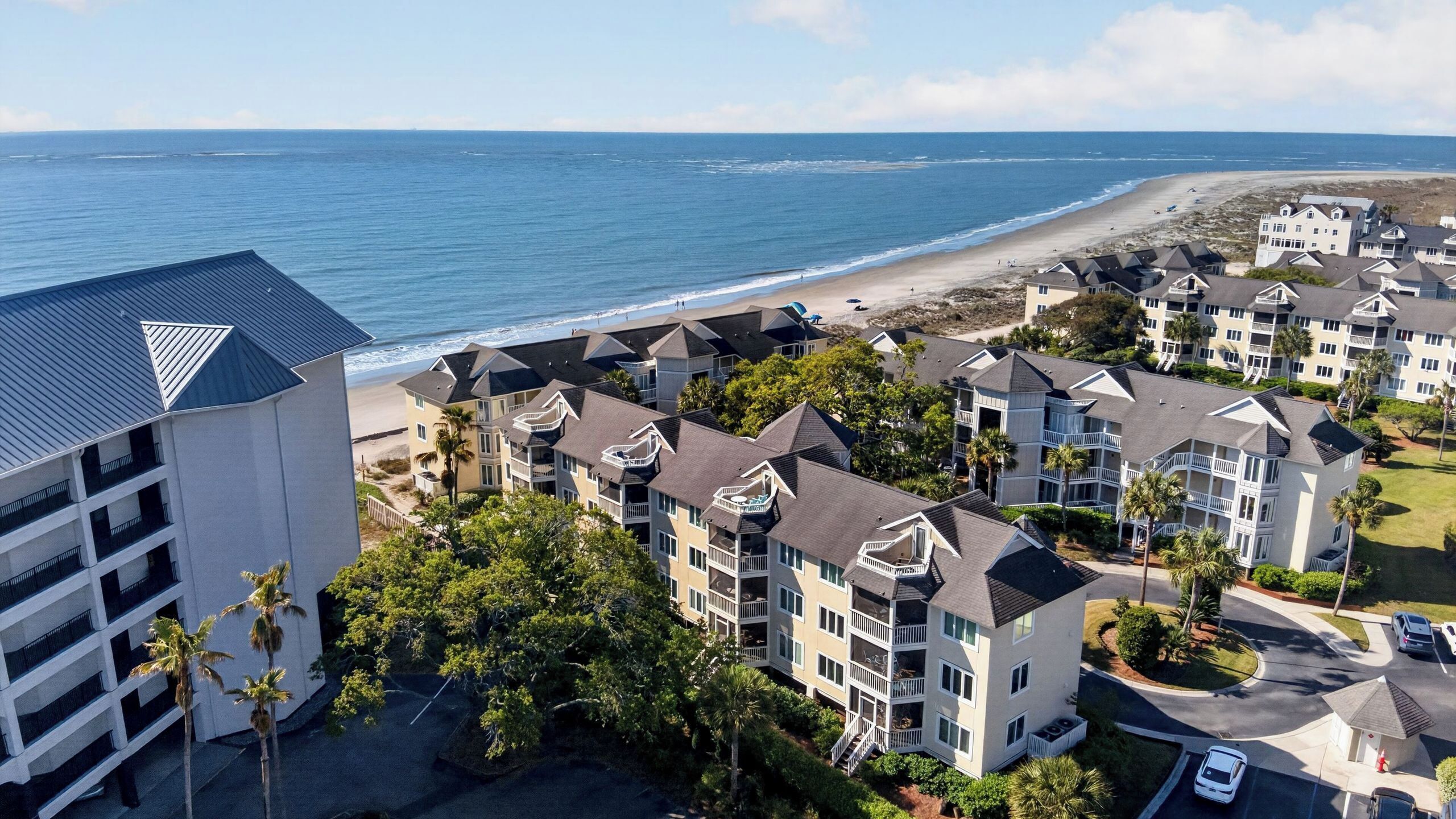 Un hôtel situé sur la côte, composé de bâtiments à plusieurs étages, doté de balcons et offrant une vue sur la plage.