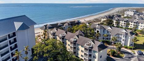 Un hôtel situé sur la côte, composé de bâtiments à plusieurs étages, doté de balcons et offrant une vue sur la plage.