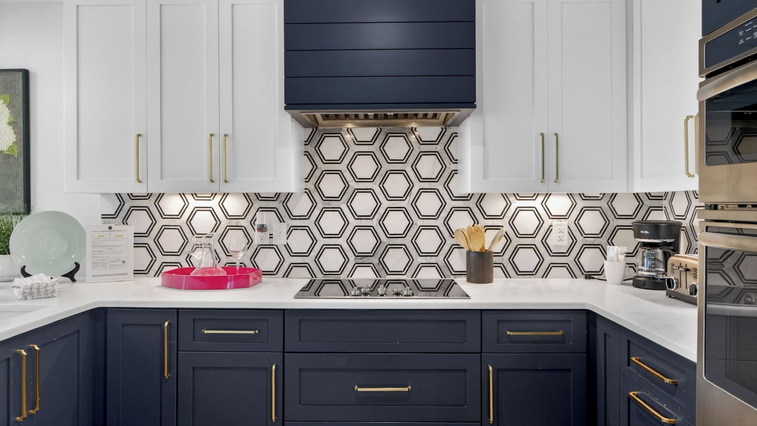 A modern kitchen with white and dark cabinets, a hexagonal backsplash, and stainless steel appliances.