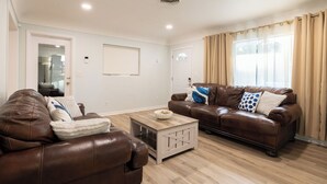 Un salon avec deux canapés en cuir marron, une table basse en bois et des rideaux beige.