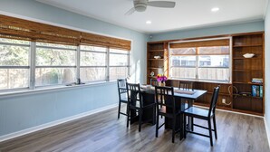 Un coin repas comprenant une table et des chaises, un ventilateur de plafond et une bibliothèque.