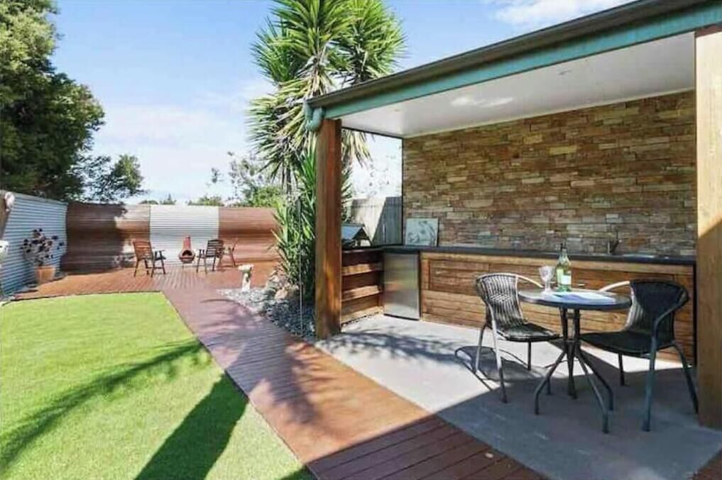 A patio with a brick wall, a wooden deck, and outdoor seating.