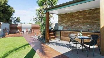 A patio with a brick wall, a wooden deck, and outdoor seating.