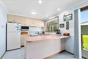 A modern kitchen with a central island, built-in appliances, and a large window providing natural light.