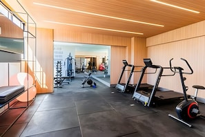Ein modernes Fitnessstudio mit Laufbändern, einem Ergometer und Gewichten.