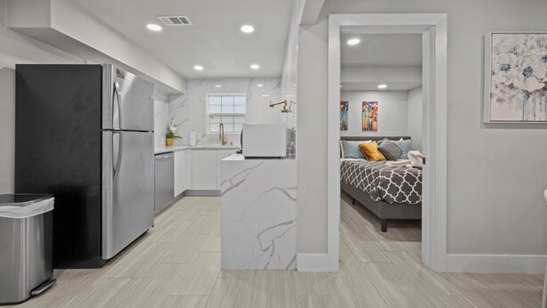A modern kitchen with stainless steel appliances, a marble island, and a dining area with a white table and chairs.