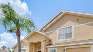 A residential building with a beige exterior, a garage, and a palm tree in the front yard. - 5bd 4bth 20 min to Disney FREE Heated POOL & Spa. 2 Master suites. (Davenport)