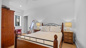 Ein Schlafzimmer mit einem hölzernen Bettgestell, zwei Nachttischen mit Lampen, einem Holzschrank und einem roten Sessel.