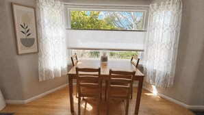 A dining area with a table and chairs, a window with blinds, a framed artwork on the wall, and a patterned rug on the floor. - Sugarhouse Retreat - Walk to Shops + Parks - Cozy Home w/ Private Yard (Salt Lake City)