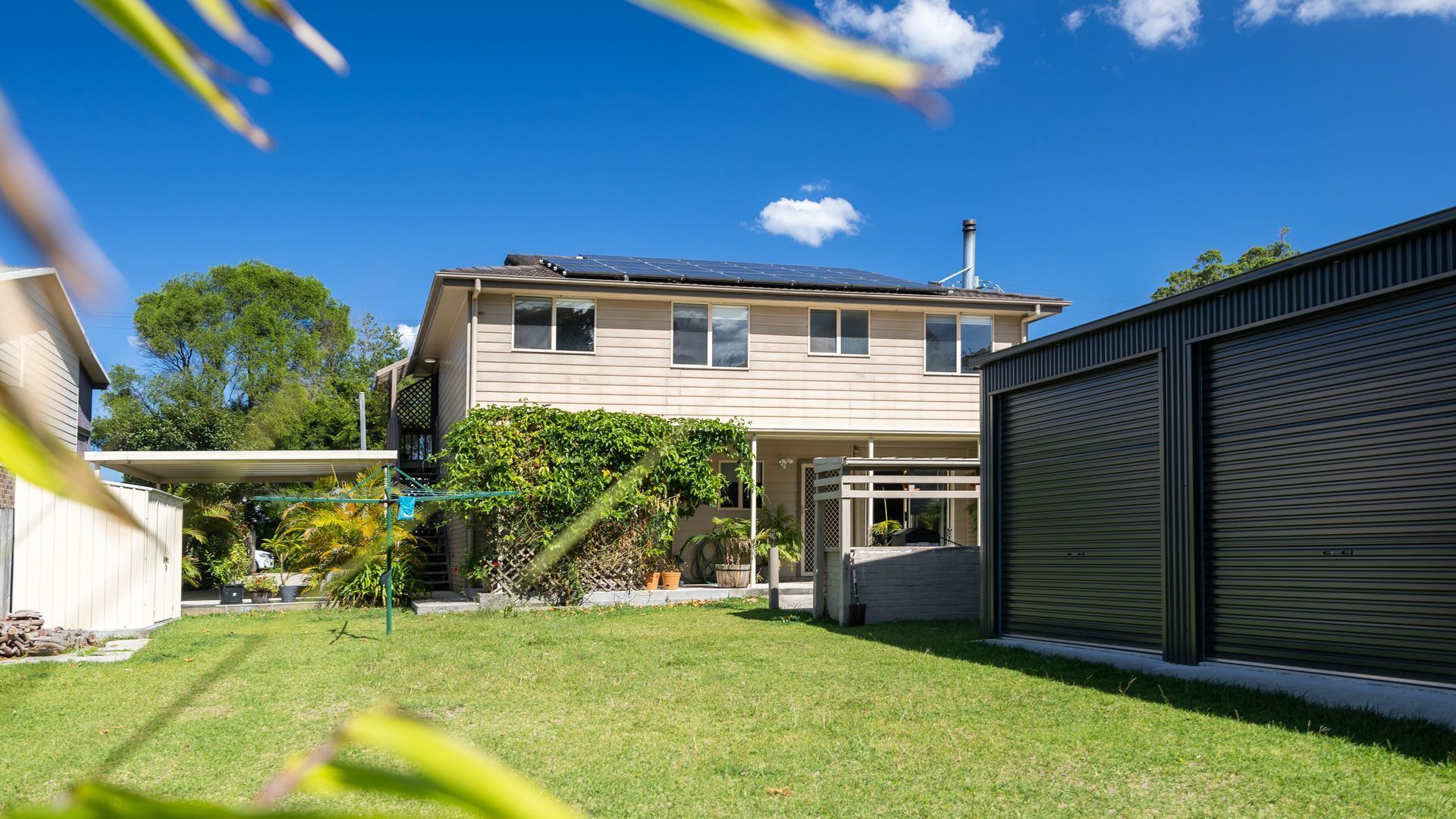 A two-story house with a covered patio, a garage, and a well-maintained lawn.