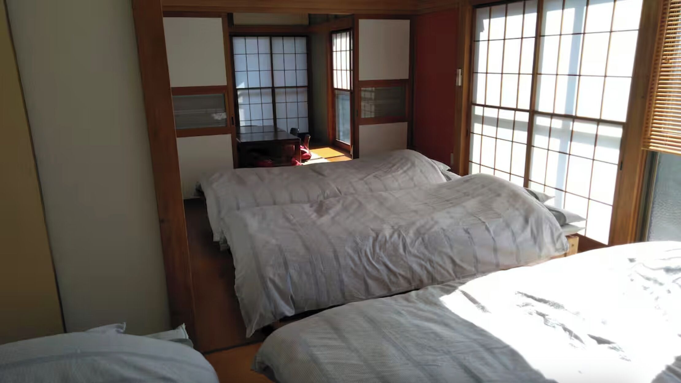 Una habitación tradicional japonesa con suelo de tatami, puertas correderas y una cama con ropa blanca.