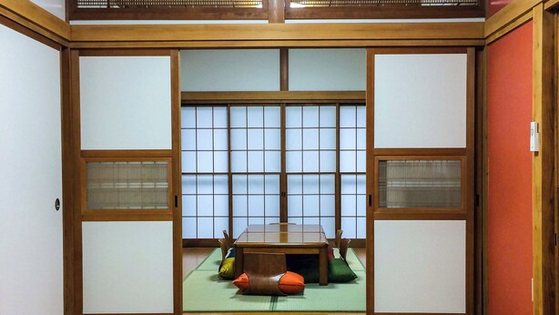 A traditional Japanese room with tatami flooring, a low table, and shoji screens. - Shiki House (Shiki)